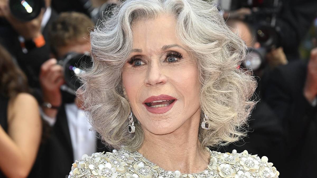 Jane Fonda standing on the red carpet with photographers behind her