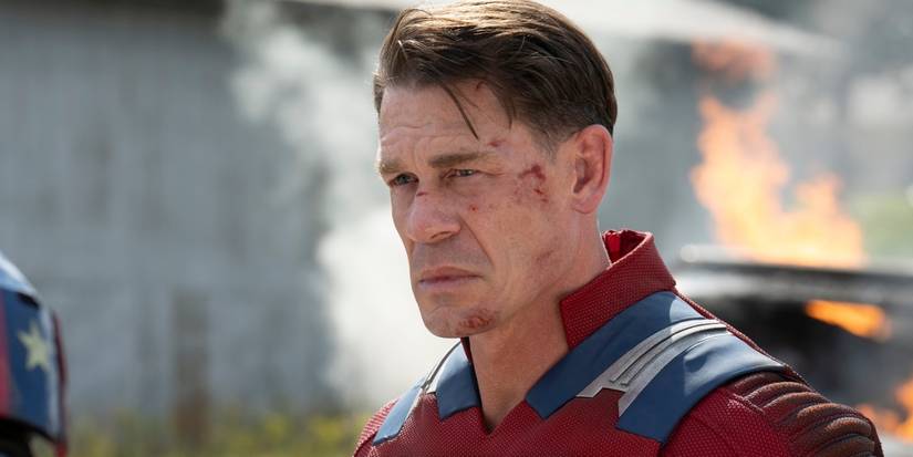 John Cena as Chris with a beaten face and wreckage behind in Peacemaker Season 2, Episode 7.