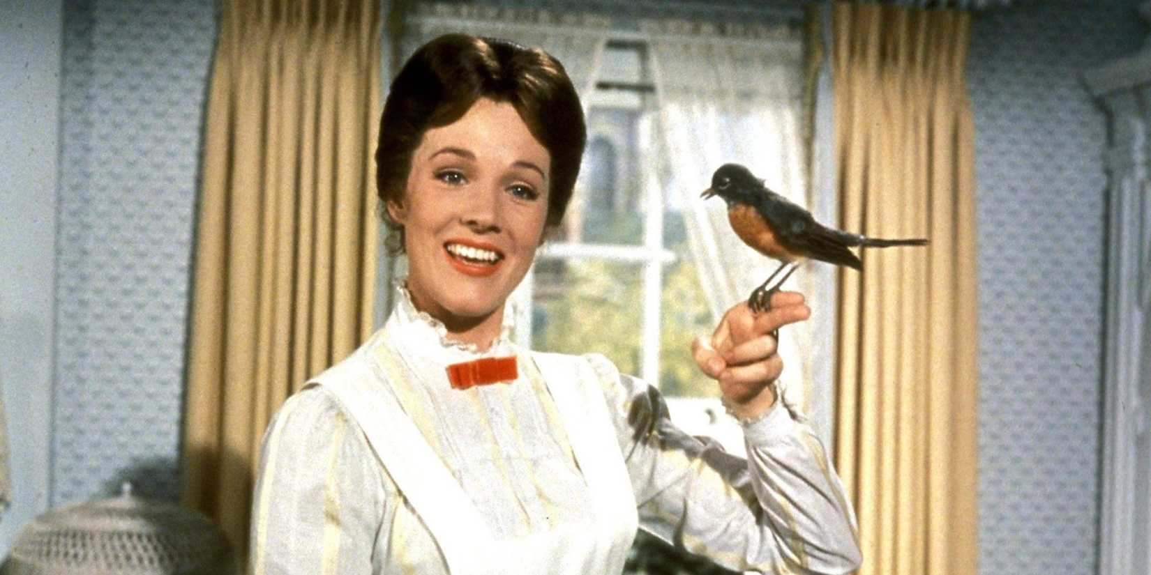 Julie Andrews as Mary Poppins smiles while a bird sits on her finger in Mary Poppins.