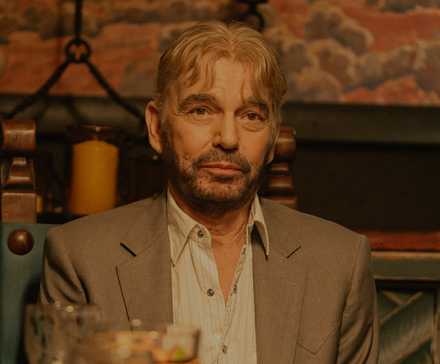Billy Bob Thornton as Tommy Norris sitting at a table in Landman