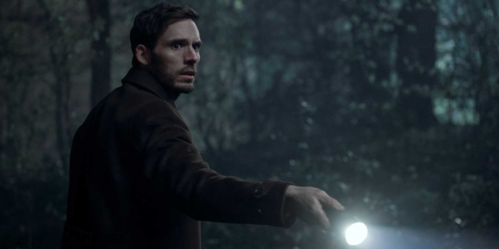Sam Claflin as Laz holding a flashlight outside in the dark in Harlan Coben's Lazarus