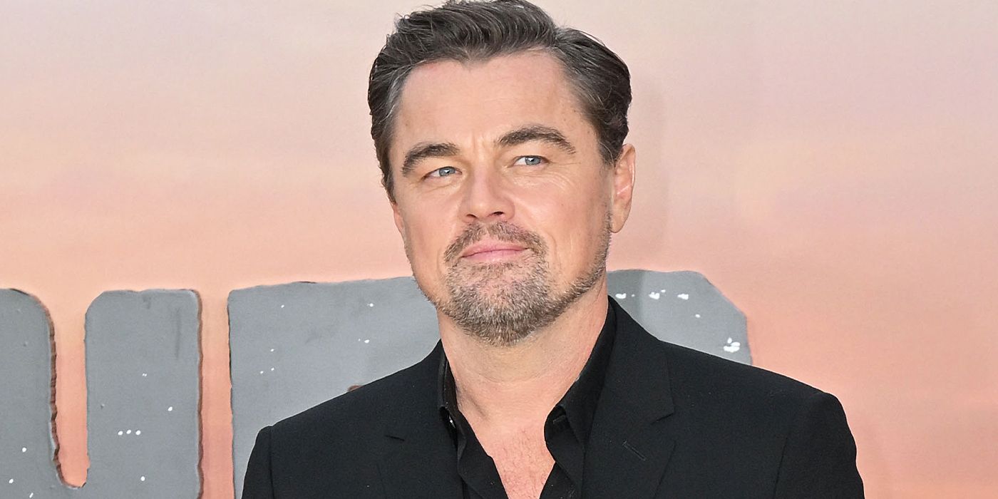 Leonardo DiCaprio wears a black shirt and poses on the red carpet