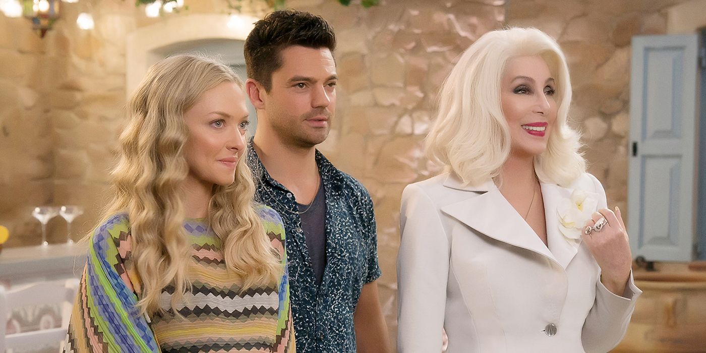 Amanda Seyfried, Dominic Cooper and Cher stand next to one another in Mamma Mia Here We Go Again