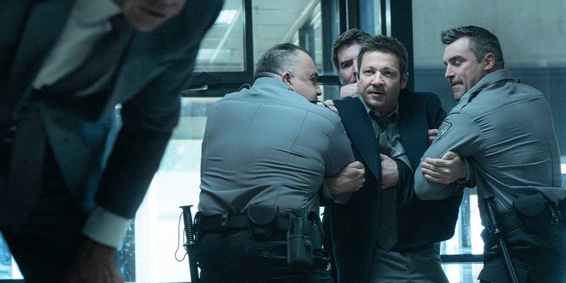 Mike is being restrained by officers, staring at a man in the foreground who's leaning over in pain.