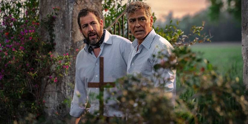 Adam Sandler and George Clooney look to the side outdoors, slightly disheveled in Jay Kelly.