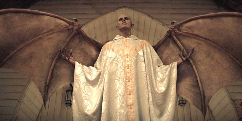 The demonic-looking "Angel" from Midnight Mass in a priest's robes standing under the dome of a church.