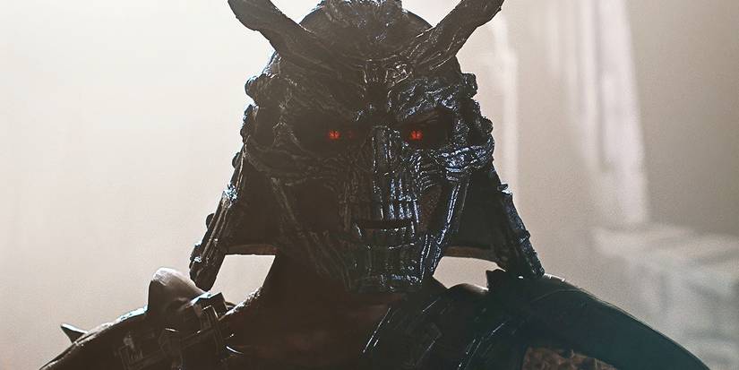 Close-up of Shao Kahn's mask with glowing red eyes.