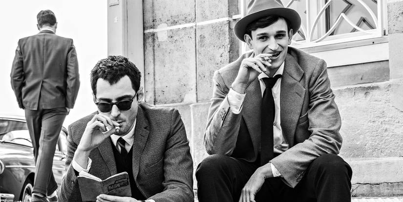 Jean-Luc Godard and Jean-Paul Belmondo sitting on steps reading and smoking.