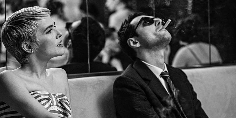 Jean Seberg and a smoking Jean-Luc Godard sitting together in front of a mirror.