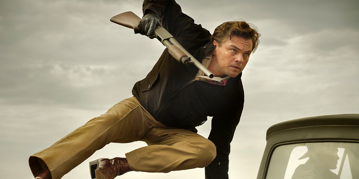 Leonardo DiCaprio as Rick Dalton jumping over a car with a gun in Once Upon a Time... in Hollywood.