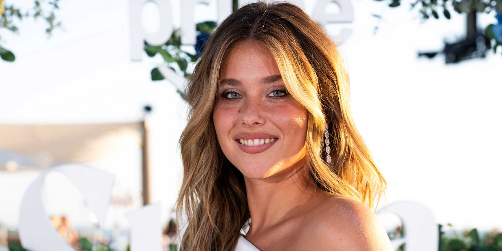 Nicole Wallace smiling in a white dress while celebrating at the Ibiza premiere of Our Fault