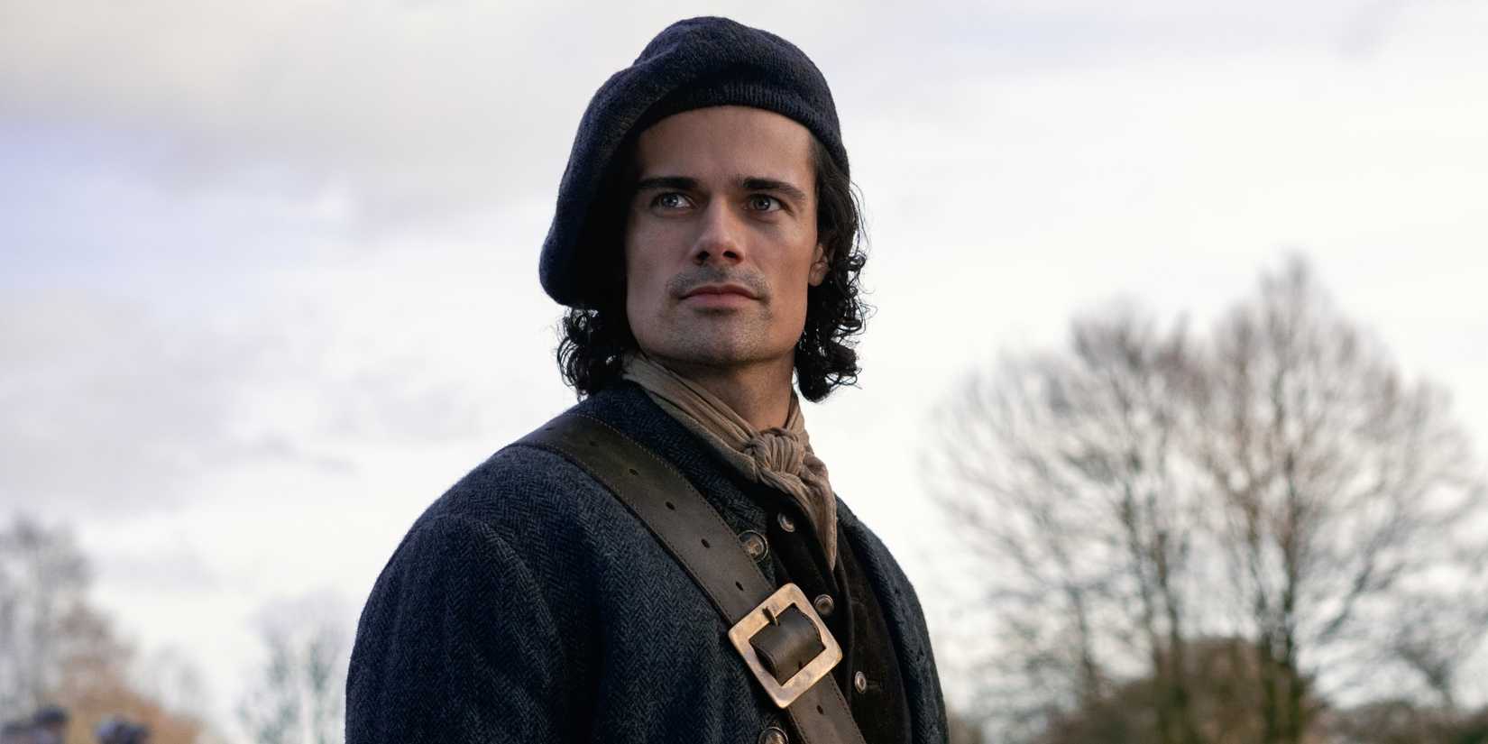 Jamie Roy as Brian Fraser standing outside in a hat and coat in Outlander: Blood of My Blood.