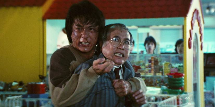 A bruised Jackie Chan holding a man hostage in Police Story