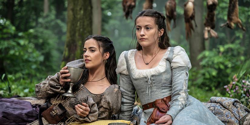 Lydia Peckham as Priscilla, Lauren McQueen as Marian sitting together in the forest