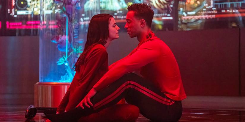 Tarima and Caleb are sitting on the floor together, looking at one another intimately.