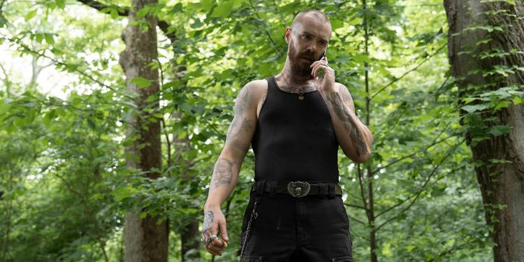 Sam Keeley talking on a cell phone while outdoors in a forest in Task Episode 7.
