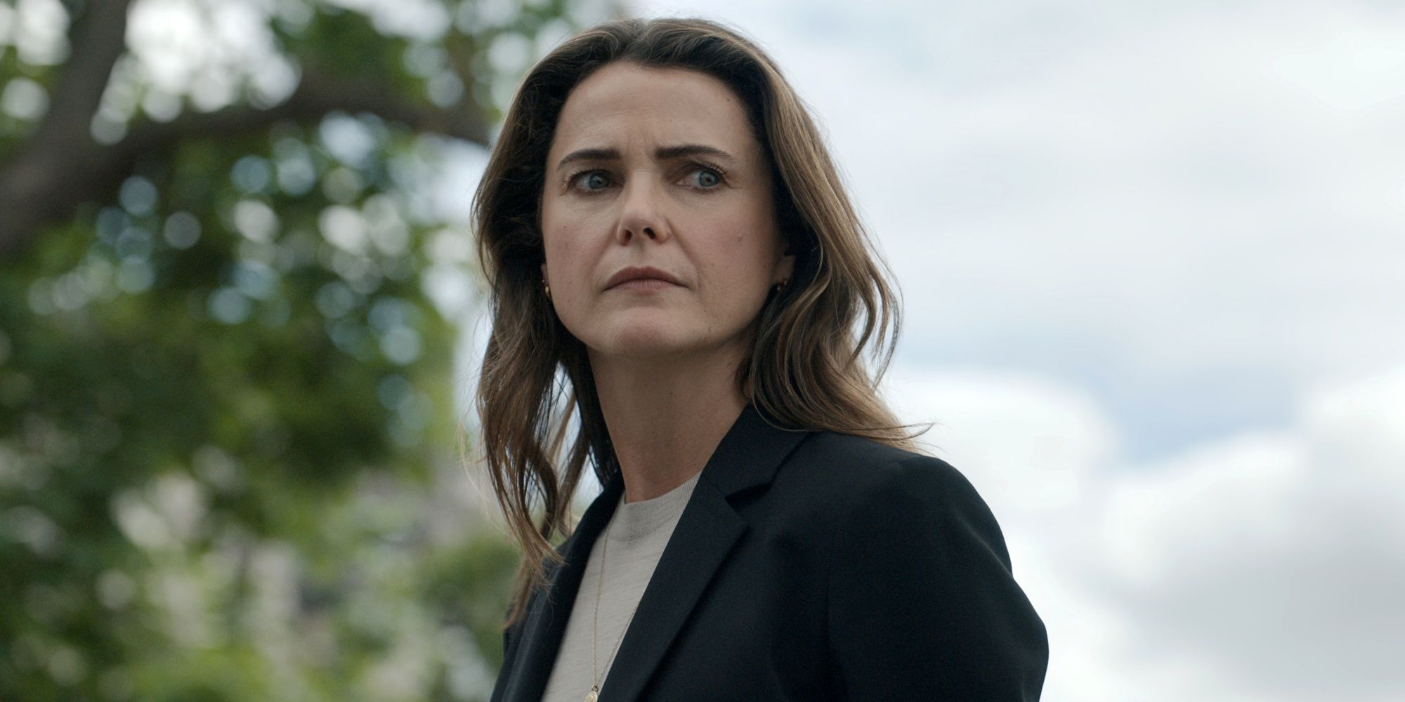 Keri Russell sebagai Kate dalam kemeja dan jas dengan rambut tergerai di The Diplomat Musim 3.