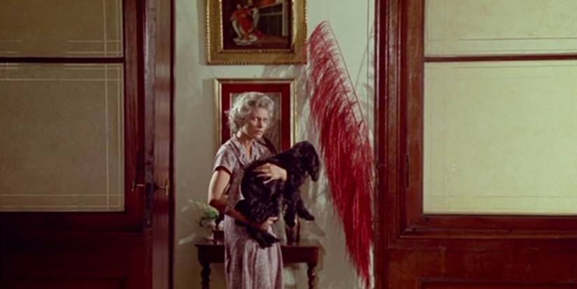 A woman carrying a black dog in The House With Laughing Windows