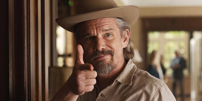 Ethan Hawke as Lee Raybon smiling while holding his right hand up in the shape of a gun in The Lowdown 