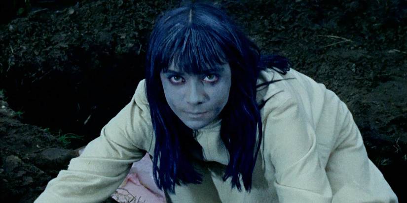 Seorang wanita undead muda berjongkok dan melihat ke arah kamera dalam The Plague of the Zombies (1966)