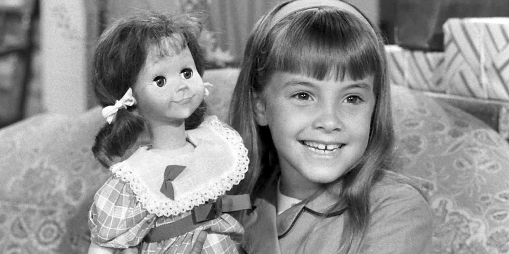 Tracy Stratford holding up a doll and smiling happily in The Twilight Zone episode Living Doll.