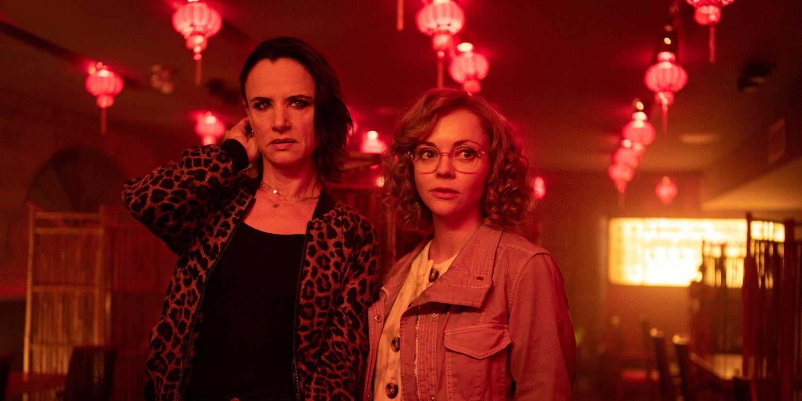 Džuljeta Lūisa kā Neta un Kristīna Riči kā Mistija istabā ar sarkanām lampiņām dzeltenās jakas.