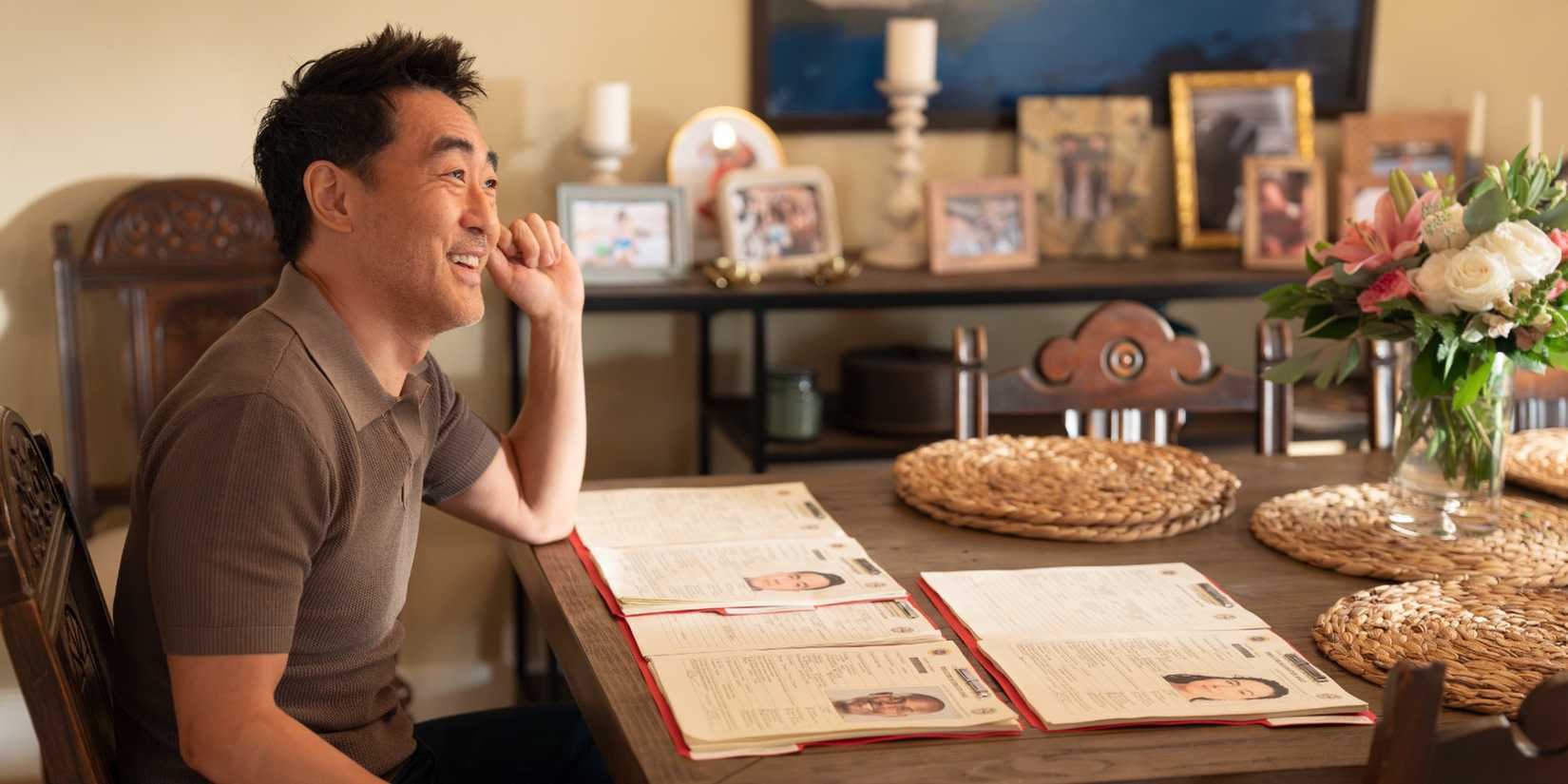 Chimney Han smiling while sitting at his kitchen table in 9-1-1 Season 9