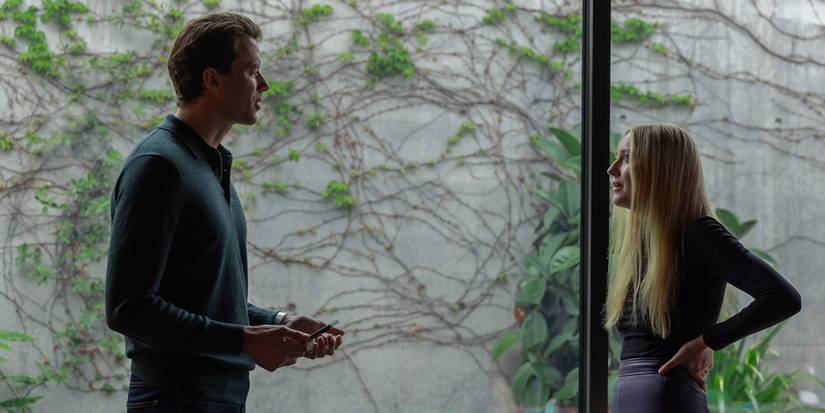Richie and Jenny talking in front of a large glass window in All Her Fault.