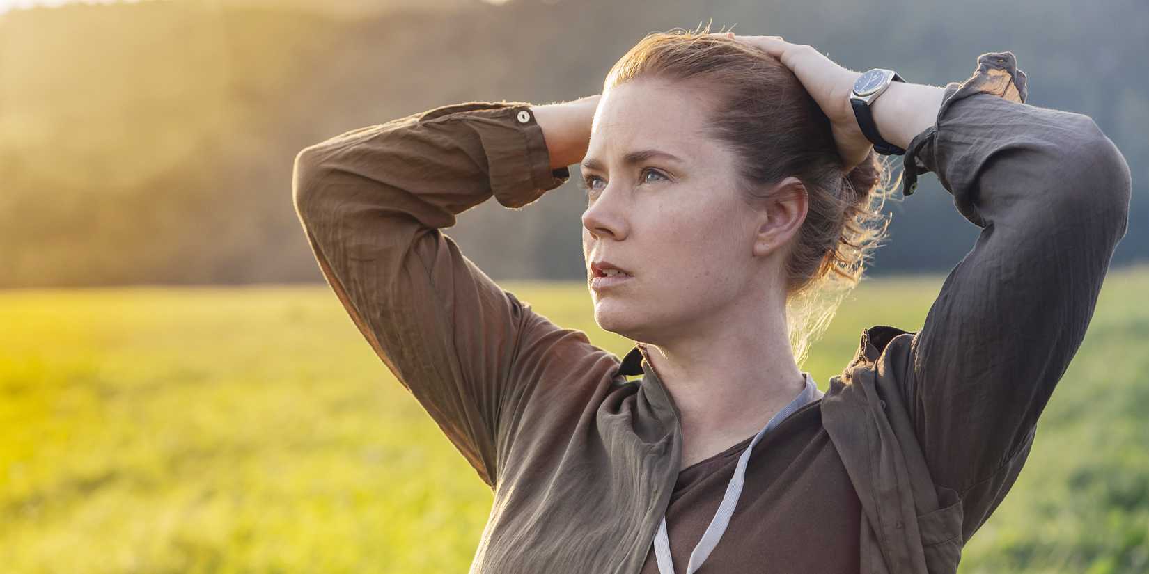 Amy Adams looking to the distance with her hands on her hair in Arrival