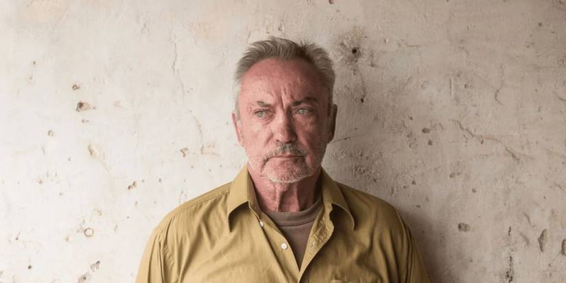 Udo Kier standing in front of a wall in Bacurau