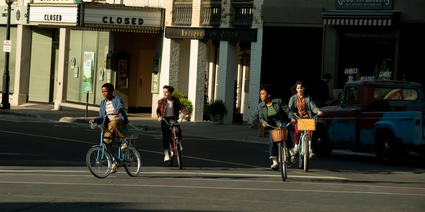 The kids of 'IT: Welcome to Derry' riding their bikes down the street past the theater