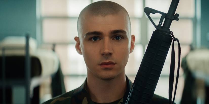 Miles Heizer as Cameron Cope holding a rifle and staring ahead towards the camera during 'Boots' episode 1.