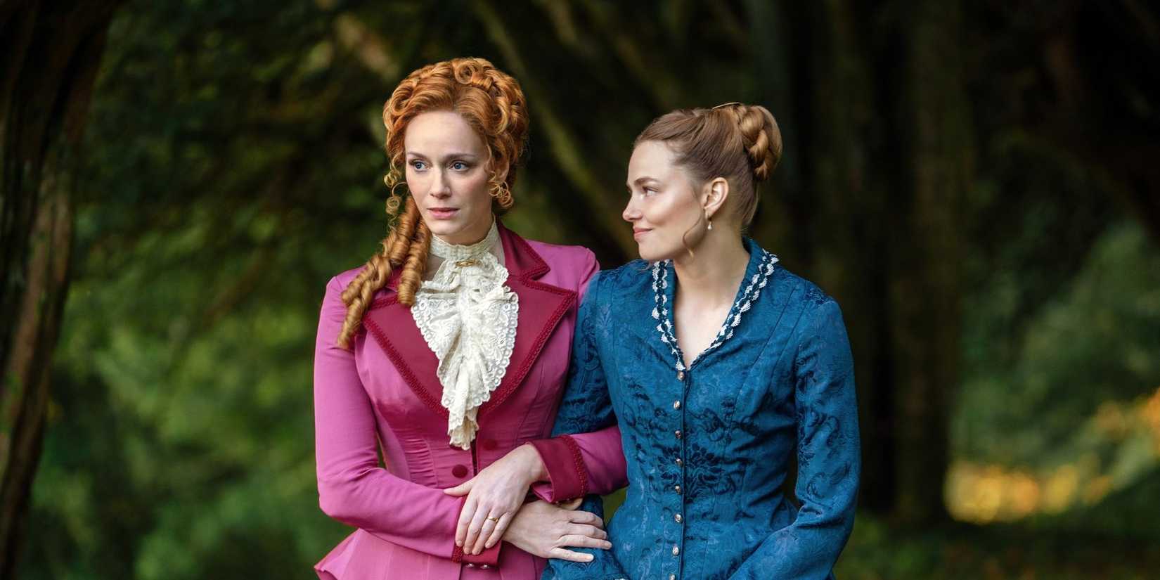 Christina Hendricks and Kristine Froseth walk arm in arm outdoors in The Buccaneers Season 2.