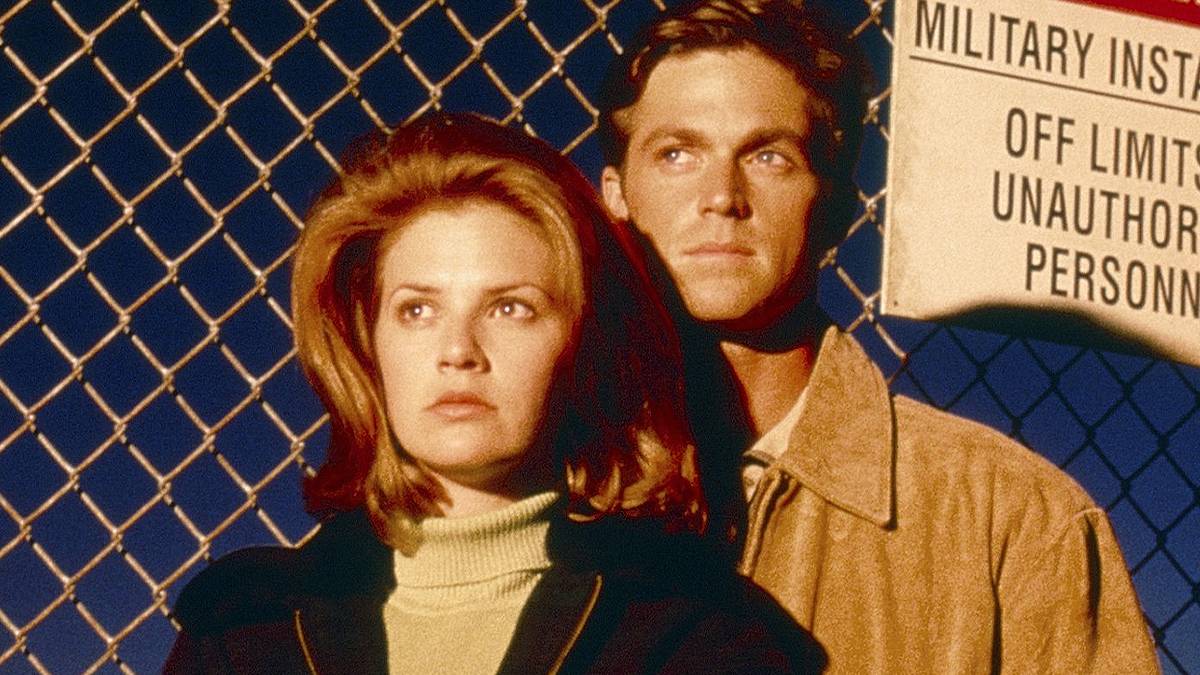 Man and woman standing against a chainlink fence