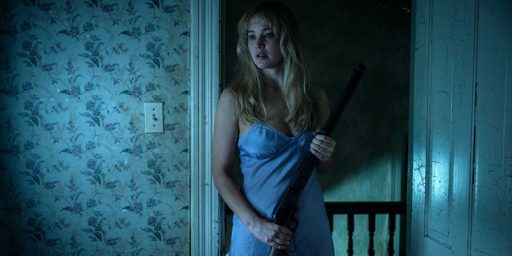 Jennifer Lawrence as Grace standing inside her house and holding a rifle in Die My Love
