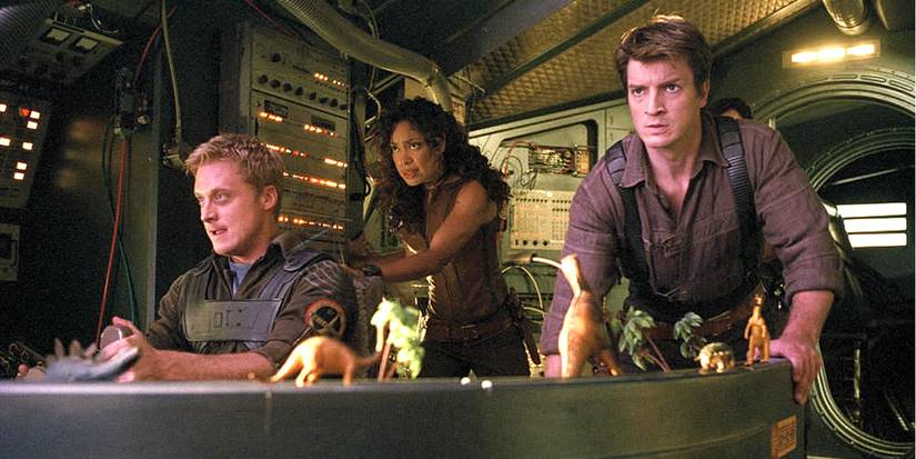 Wash, Mal, and Zoe face danger and look tense inside their ship in Firefly.