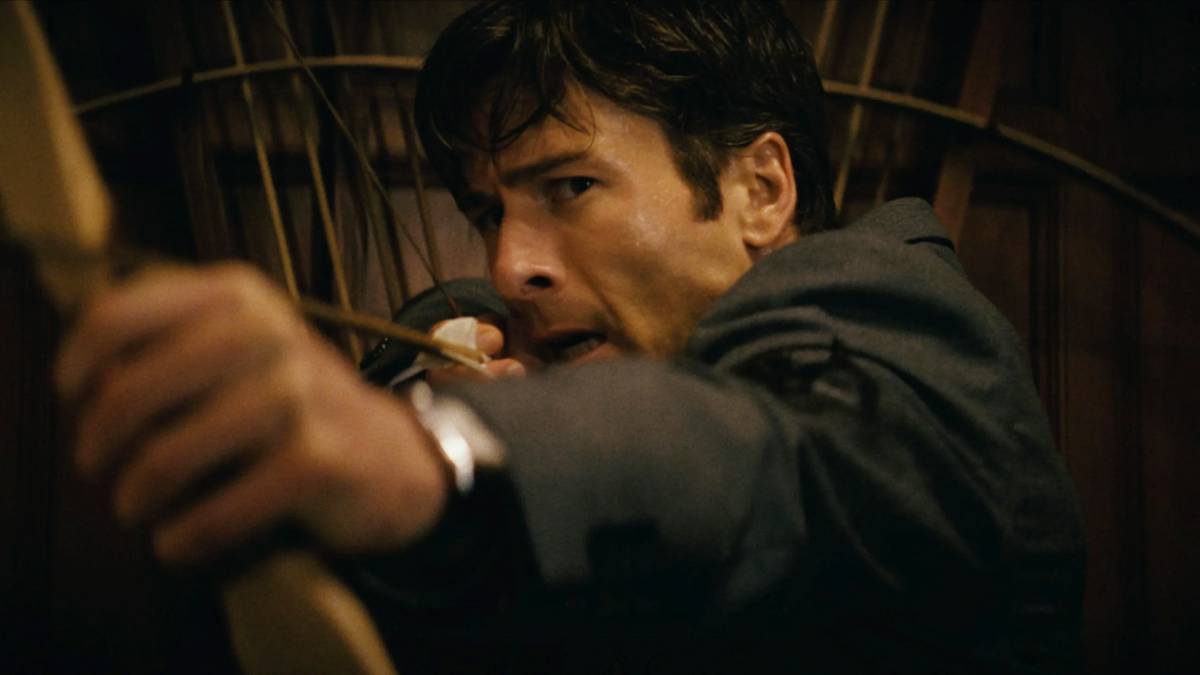 Glen Powell drawing a bow and arrow in How to Make a Killing