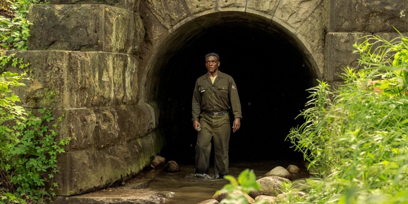 Chris Chalk as Dick Hallorann coming out of a sewer tunnel into the woods in IT: Welcome to Derry