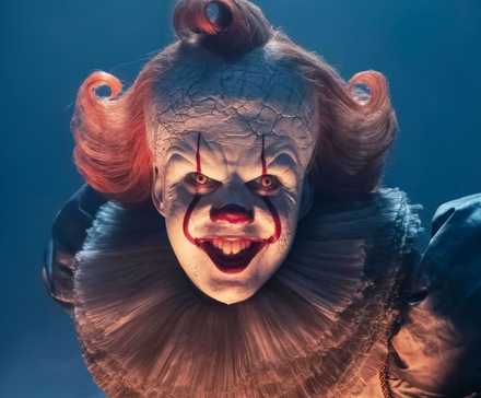 Bill Skarsgard as Pennywise bending over and smiling for the camera in It: Welcome to Derry.