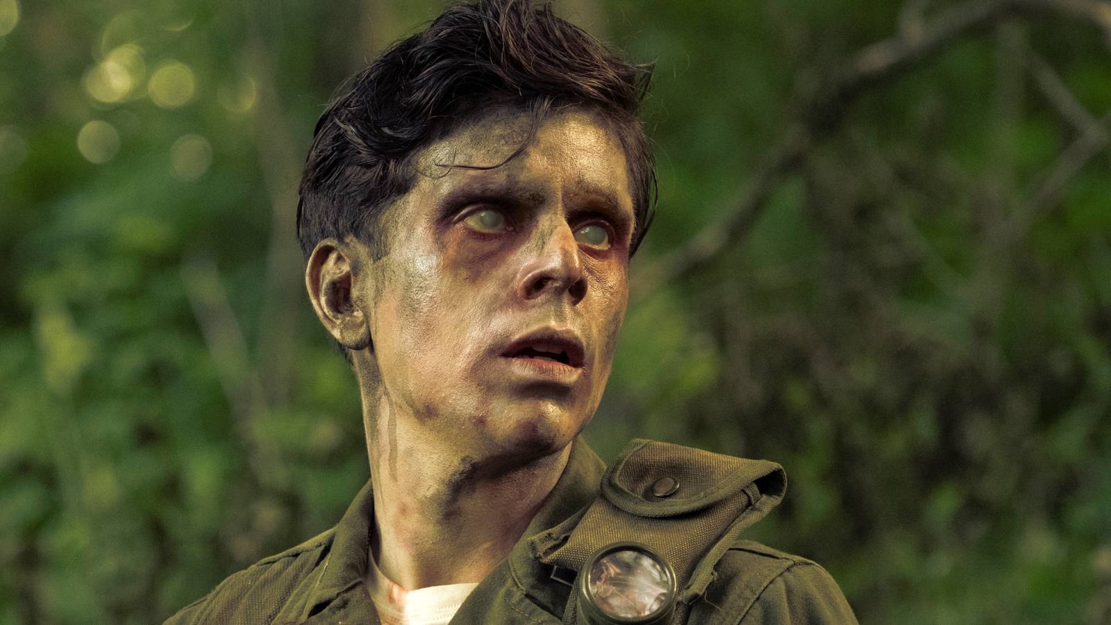 Rudy Mancuso as Captain Pauly Russo looking to the left in the woods with cloudy eyes in IT: Welcome to Derry