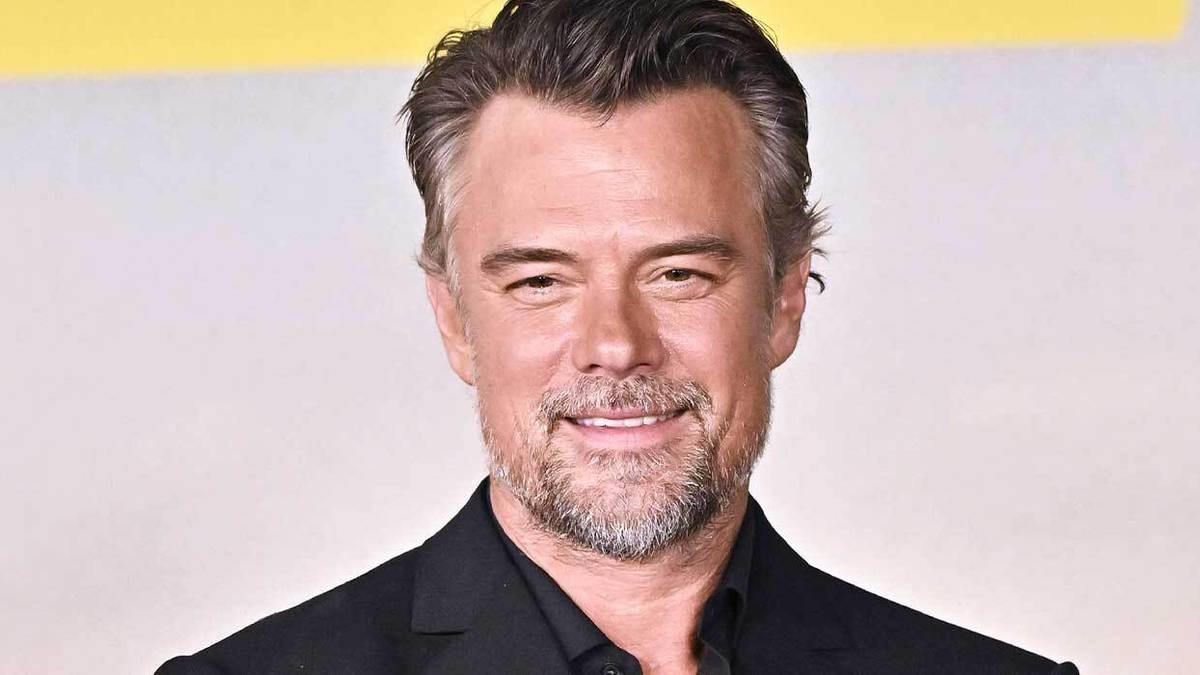Josh Duhamel wears a black shirt and attends a red carpet