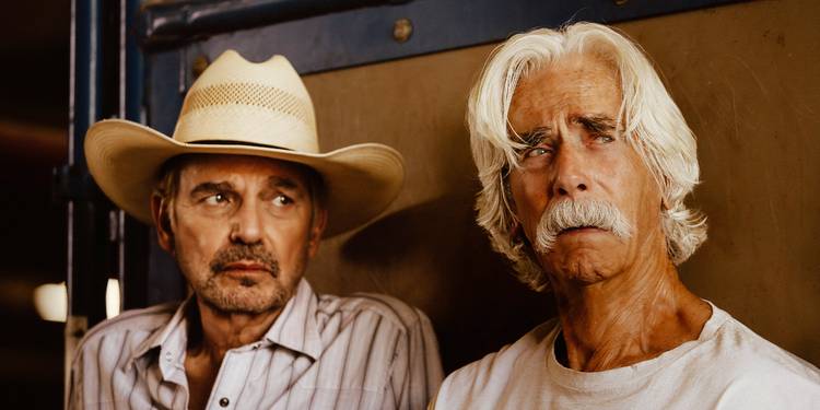 Tommy Norris in a cowboy hat looks over at his father T.L. Norris, who's looking away tearfully in Landman.