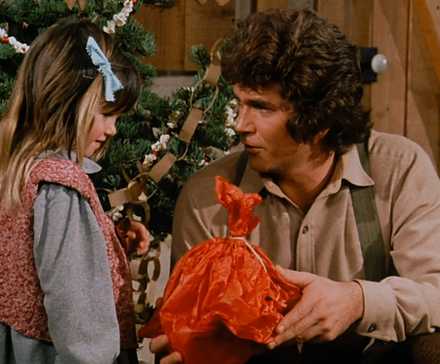Charles (Michael Landon) opens Carrie's (Lindsay Sidney Greenbush) present in the 'Little House on the Prairie' episode