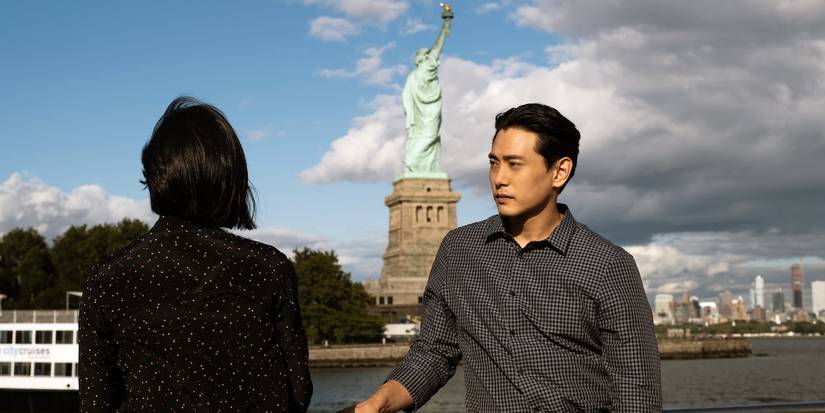 Greta Lee and Teo Yoo with the Statue of Liberty in the background in Past Lives