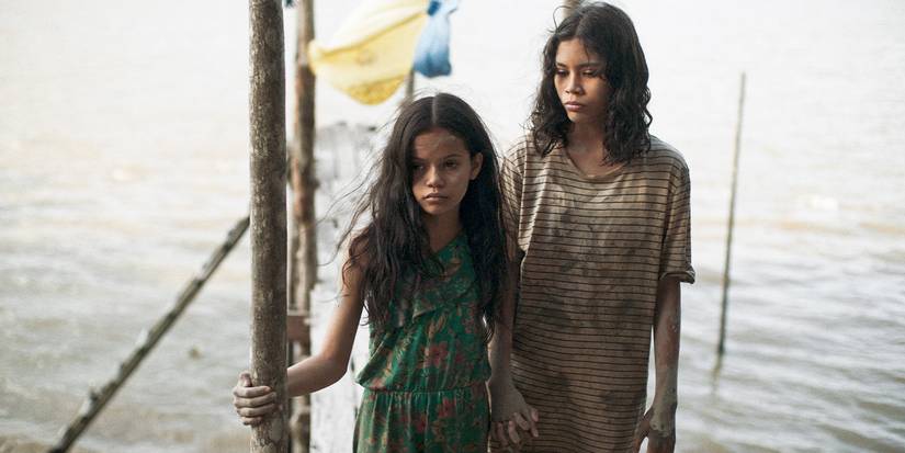 Marcielle holder her younger sister's hand on a dock by water. 