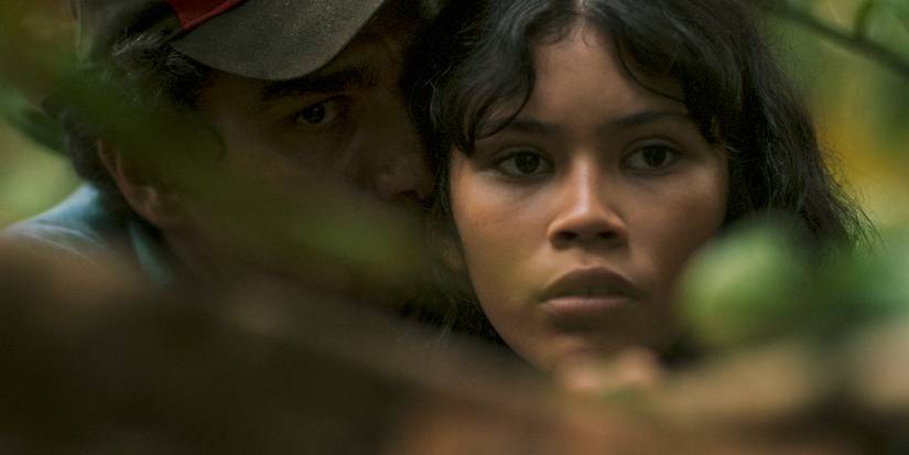 Close-up of Marcielle hunting in the Amazon rainforest with a man at her shoulder teaching her to shoot.