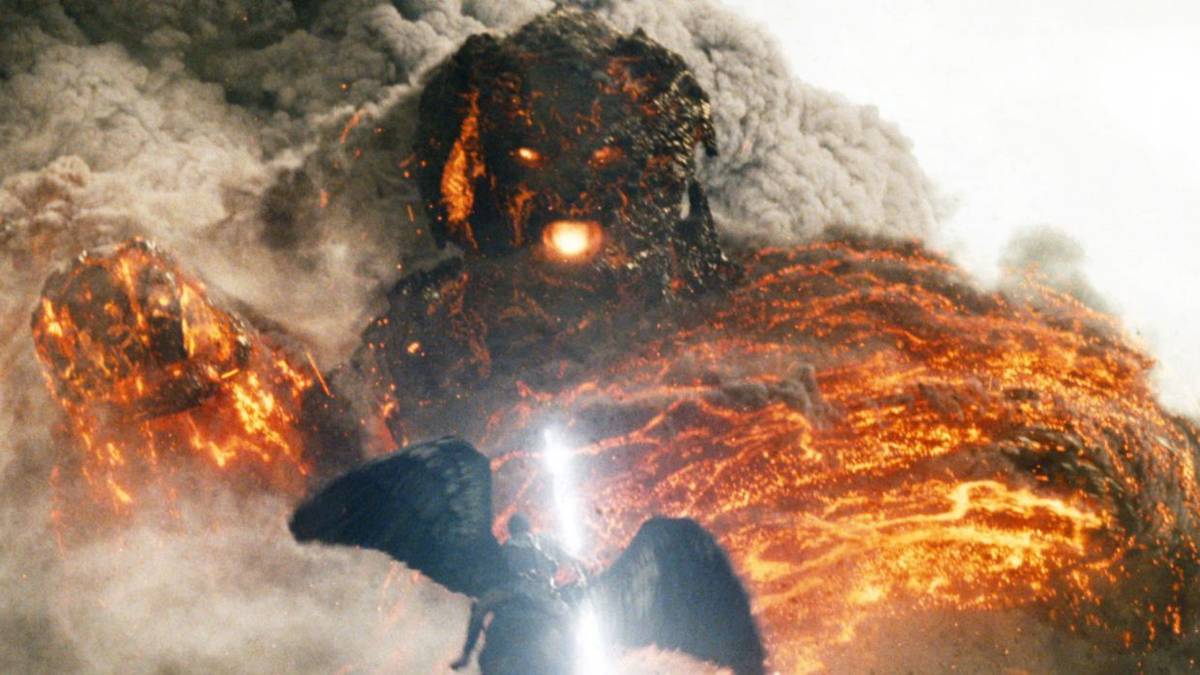 A titan towers over a human, fire and destruction, in Wrath of the Titans