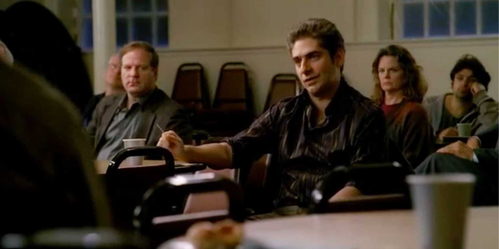 Michael Imperioli as Christopher Moltisanti sitting in a room with other people around him in The Sopranos episode Walk Like a Man