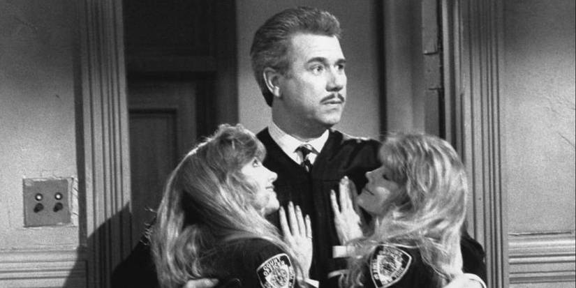 John Larroquette looks surprised with two women embracing him in Night Court Season 8, Episode 18.