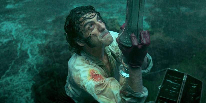 Oscar Isaac as Victor Frankenstein holding onto a spire in the rain in 'Frankenstein'
